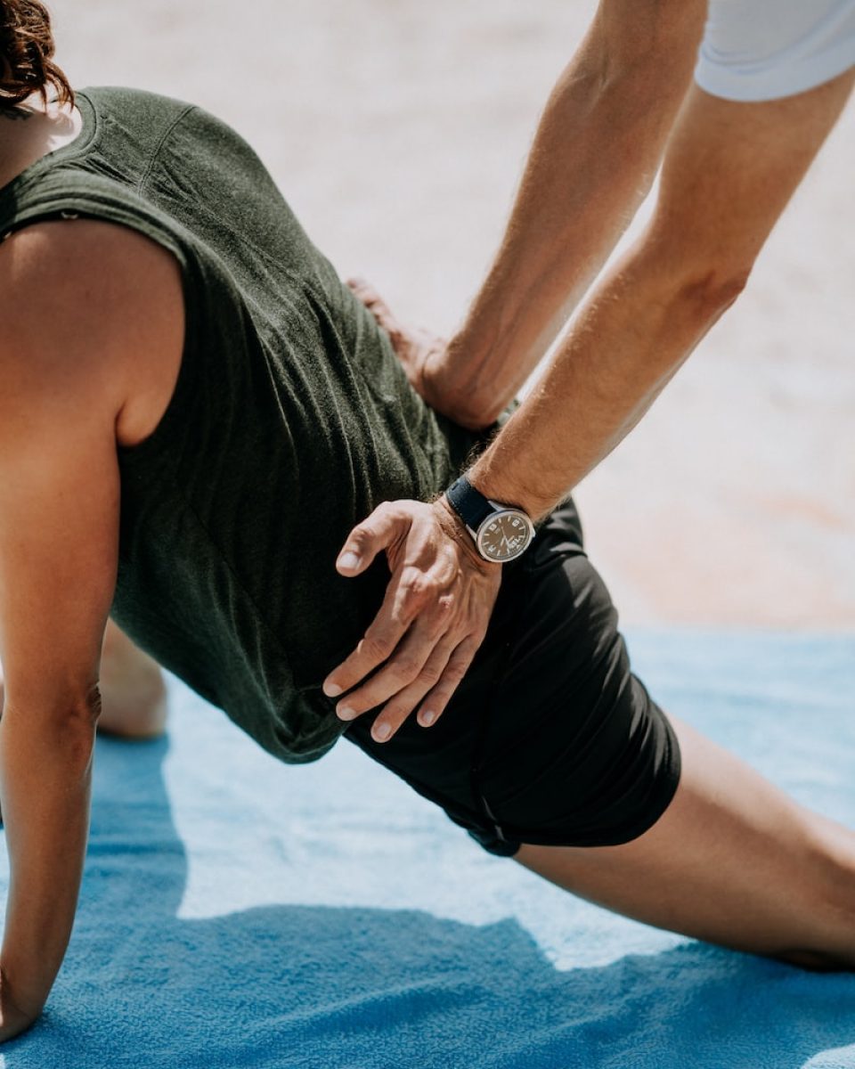 person pressing man back kneeling on blue towel